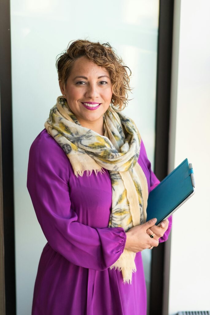 pexels-photo-1181424-1181424-1 Smiling woman in a purple dress and scarf holding a tablet indoors.